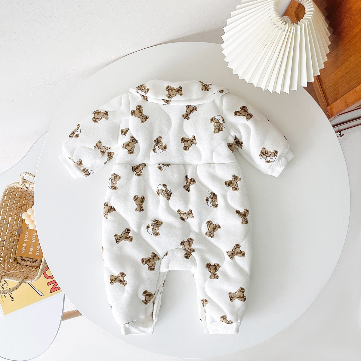 Baby wearing a thickened quilted winter romper with a cartoon bear print, showcasing a cozy and stylish design in white and apricot colors.
