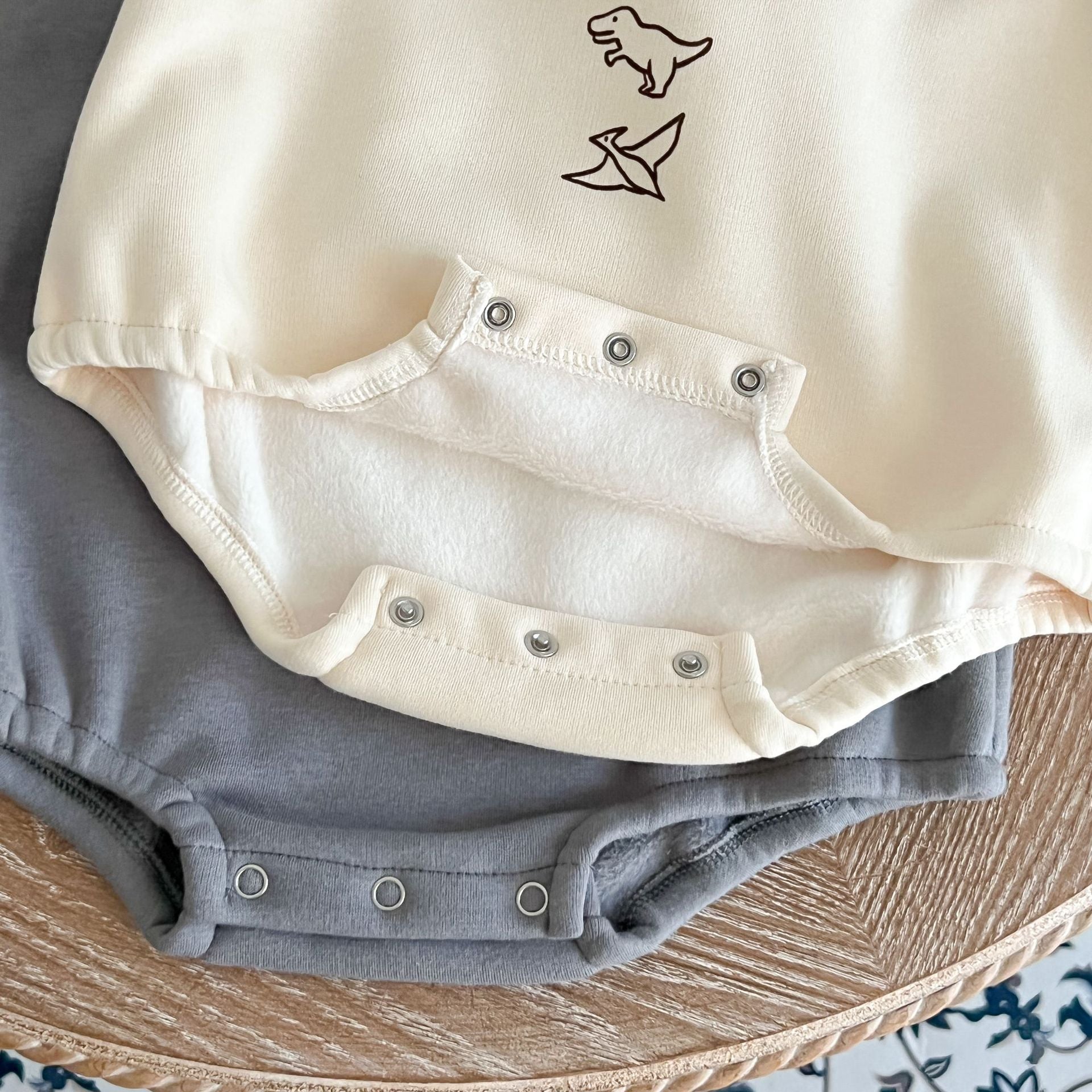 A cozy baby pullover onesie featuring a playful dinosaur print, perfect for autumn wear in apricot and brown colors.