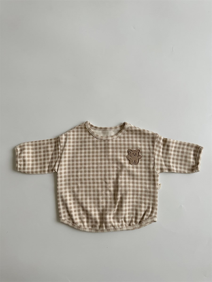 A cute baby shirt featuring a dot pattern and cartoon bear patches, made from soft cotton fabric, available in beige, apricot, and brown colors.