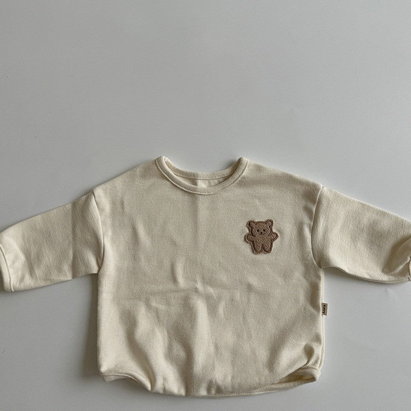 A cute baby shirt featuring a dot pattern and cartoon bear patches, made from soft cotton fabric, available in beige, apricot, and brown colors.