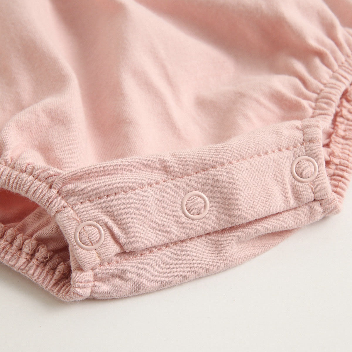 A collection of baby sleeveless onesies in pink and yellow with embroidered patterns, perfect for summer wear.