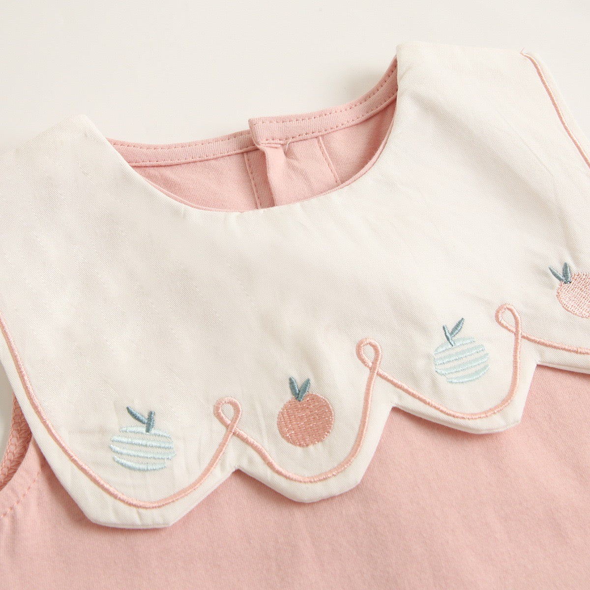 A collection of baby sleeveless onesies in pink and yellow with embroidered patterns, perfect for summer wear.