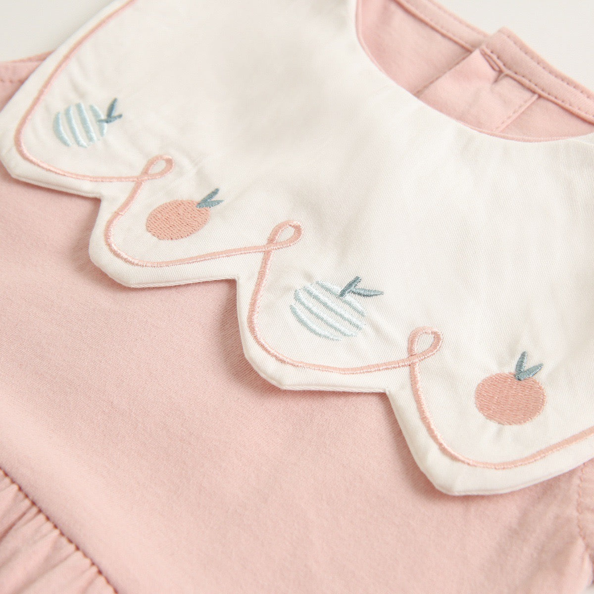 A collection of baby sleeveless onesies in pink and yellow with embroidered patterns, perfect for summer wear.