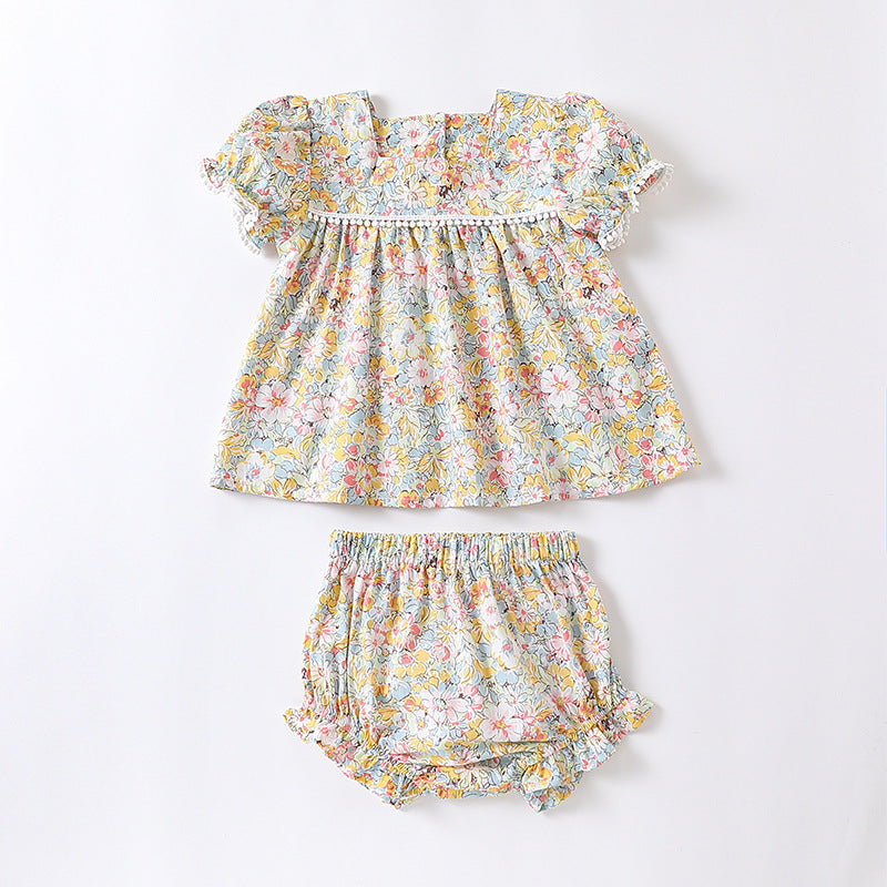 Baby girl wearing a floral pattern onesie in yellow and apricot, showcasing a stylish summer outfit.