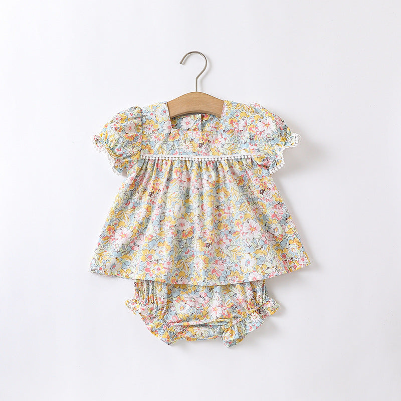 Baby girl wearing a floral pattern onesie in yellow and apricot, showcasing a stylish summer outfit.
