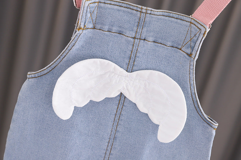 Baby girl wearing a stylish denim overall with 3D wing patches, showcasing a playful and fashionable design.