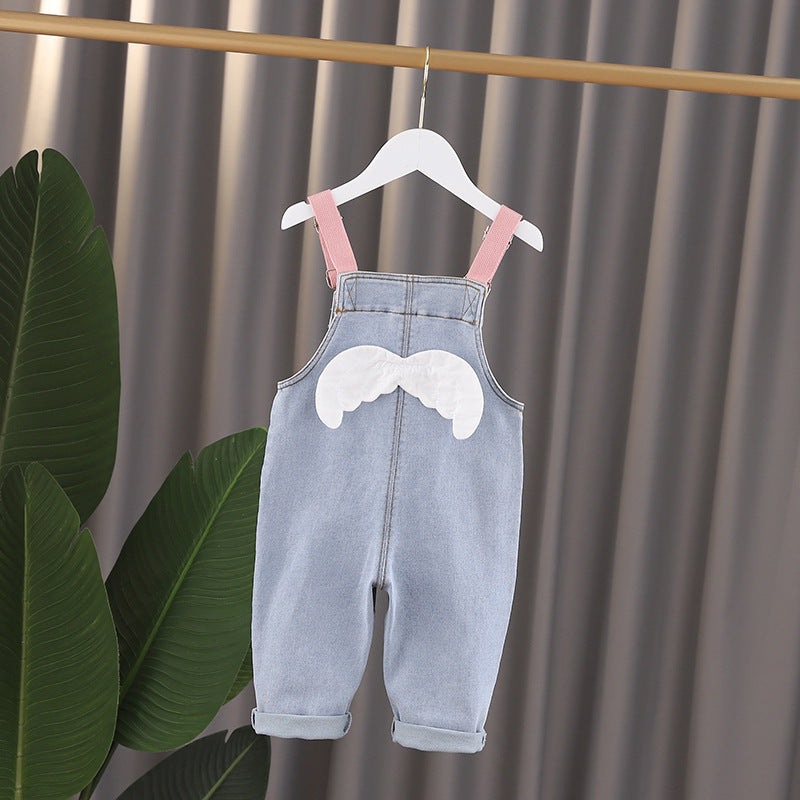 Baby girl wearing a stylish denim overall with 3D wing patches, showcasing a playful and fashionable design.
