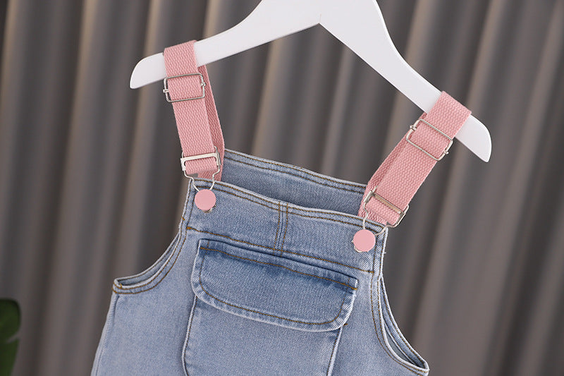 Baby girl wearing a stylish denim overall with 3D wing patches, showcasing a playful and fashionable design.