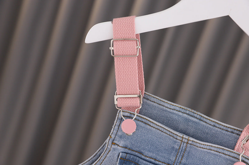 Baby girl wearing a stylish denim overall with 3D wing patches, showcasing a playful and fashionable design.