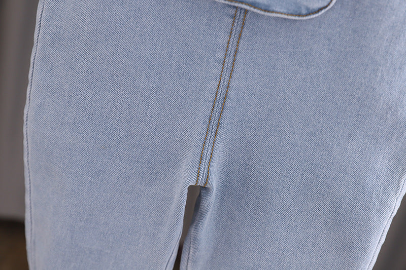 Baby girl wearing a stylish denim overall with 3D wing patches, showcasing a playful and fashionable design.