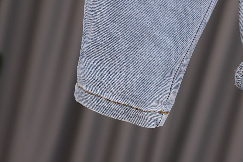 Baby girl wearing a stylish denim overall with 3D wing patches, showcasing a playful and fashionable design.