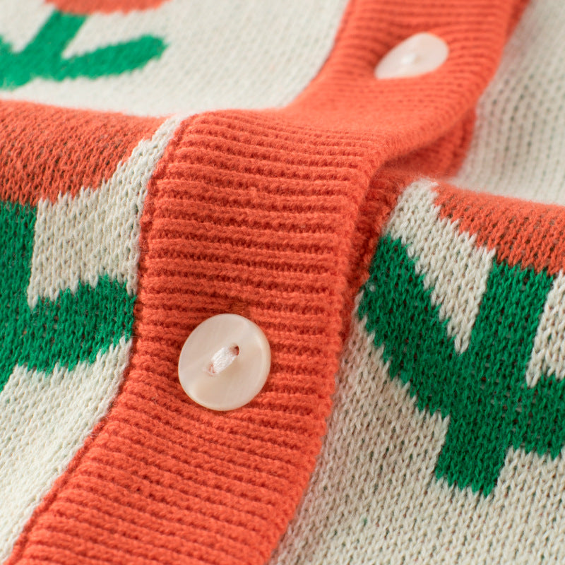 A cozy baby girl knitted cardigan featuring a vibrant floral pattern in orange, perfect for autumn outfits.