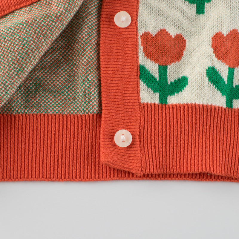 A cozy baby girl knitted cardigan featuring a vibrant floral pattern in orange, perfect for autumn outfits.