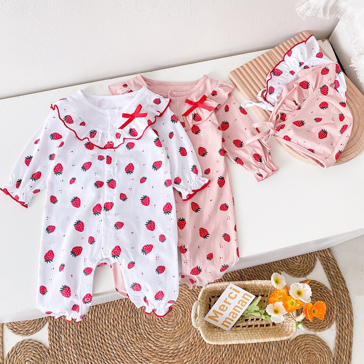 Baby girl romper featuring an allover strawberries pattern with ruffle design and button front, available in white and pink colors.