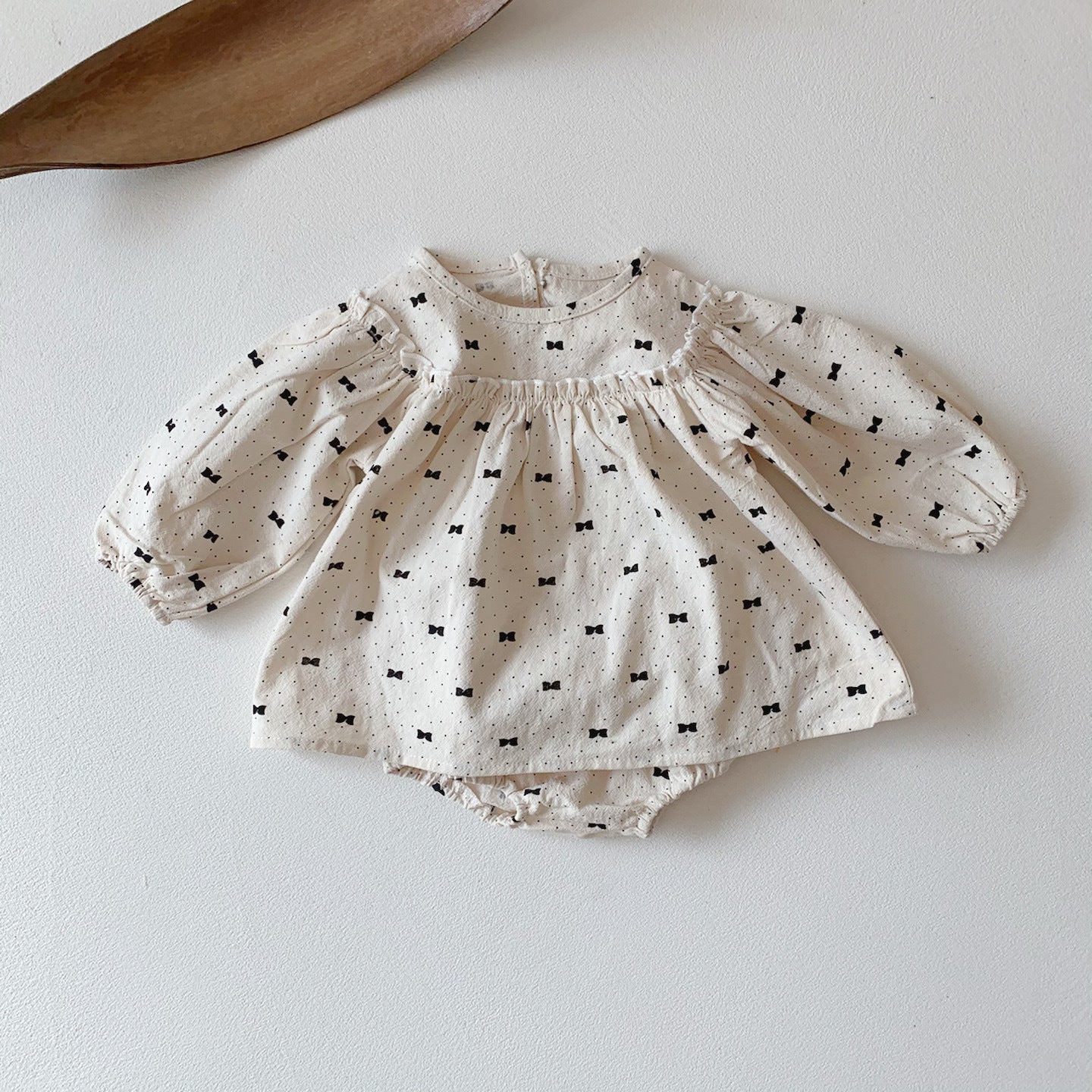 Baby girl wearing a stylish bow and polka dot A-line long sleeves shirt combo in apricot color.