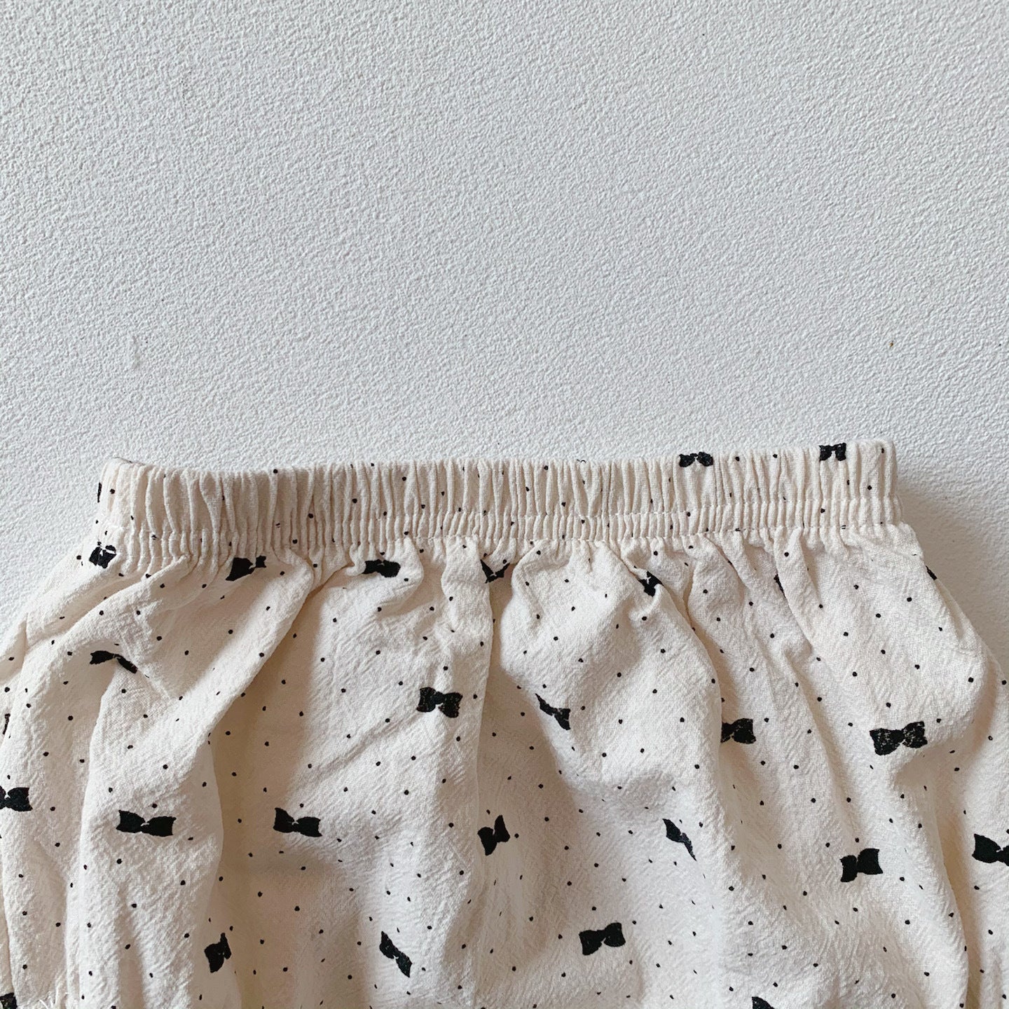 Baby girl wearing a stylish bow and polka dot A-line long sleeves shirt combo in apricot color.