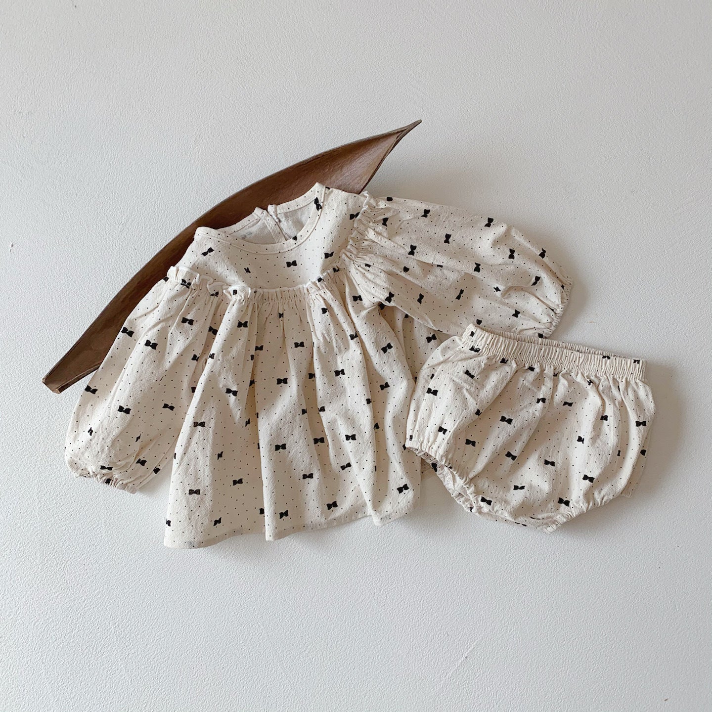 Baby girl wearing a stylish bow and polka dot A-line long sleeves shirt combo in apricot color.