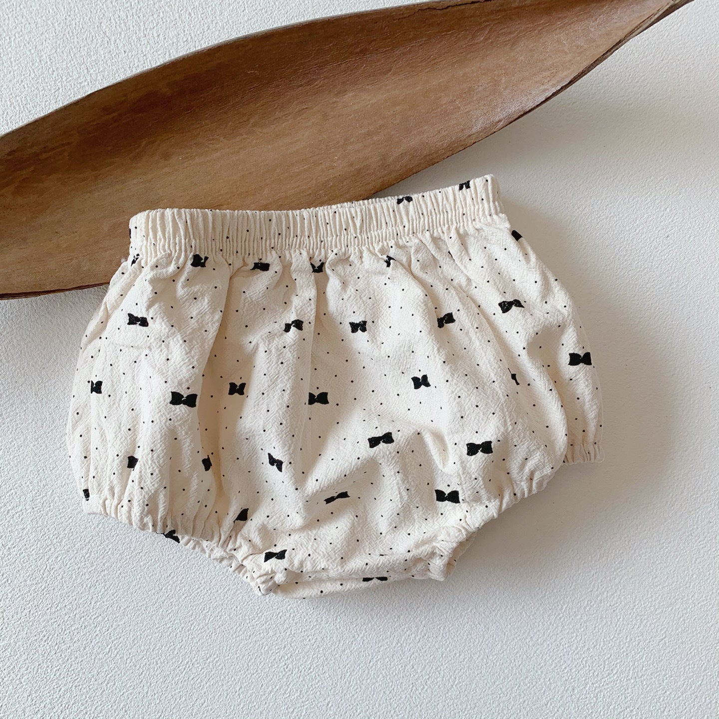 Baby girl wearing a stylish bow and polka dot A-line long sleeves shirt combo in apricot color.