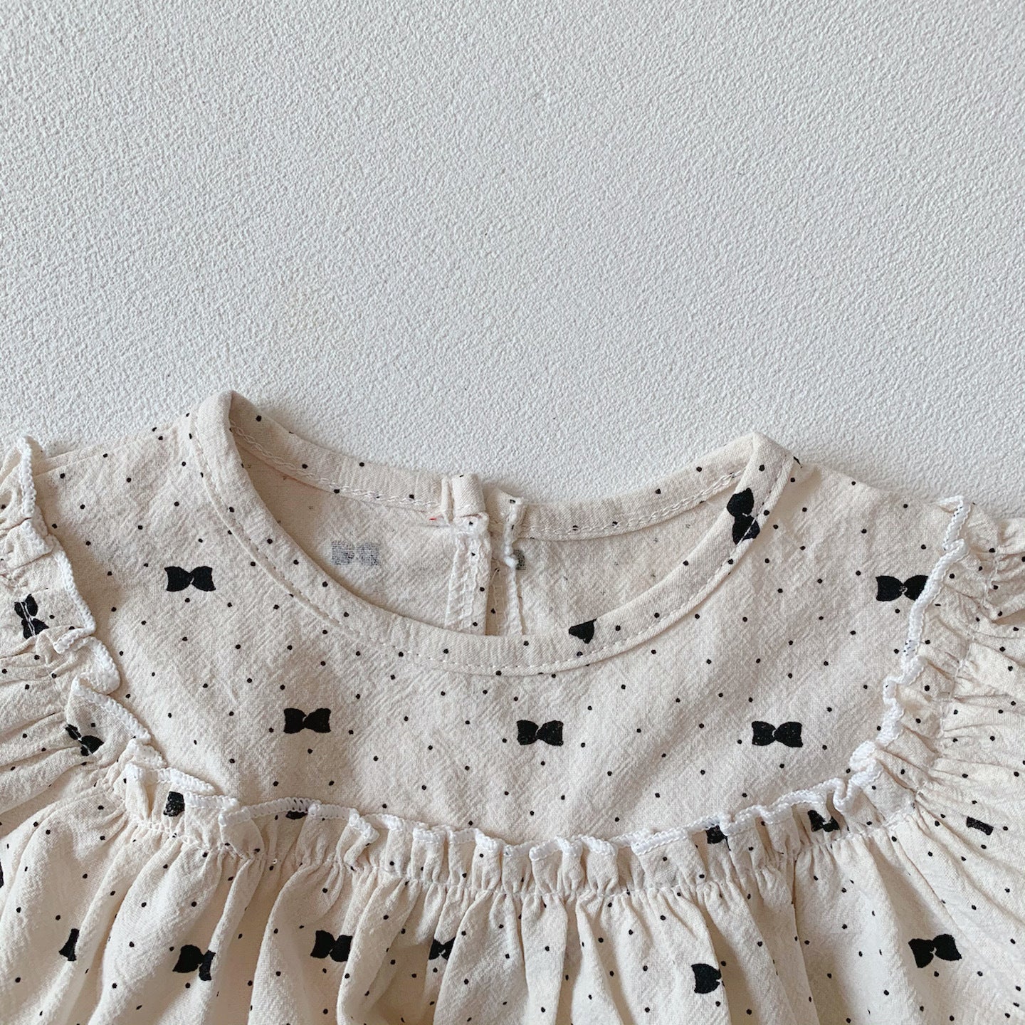 Baby girl wearing a stylish bow and polka dot A-line long sleeves shirt combo in apricot color.