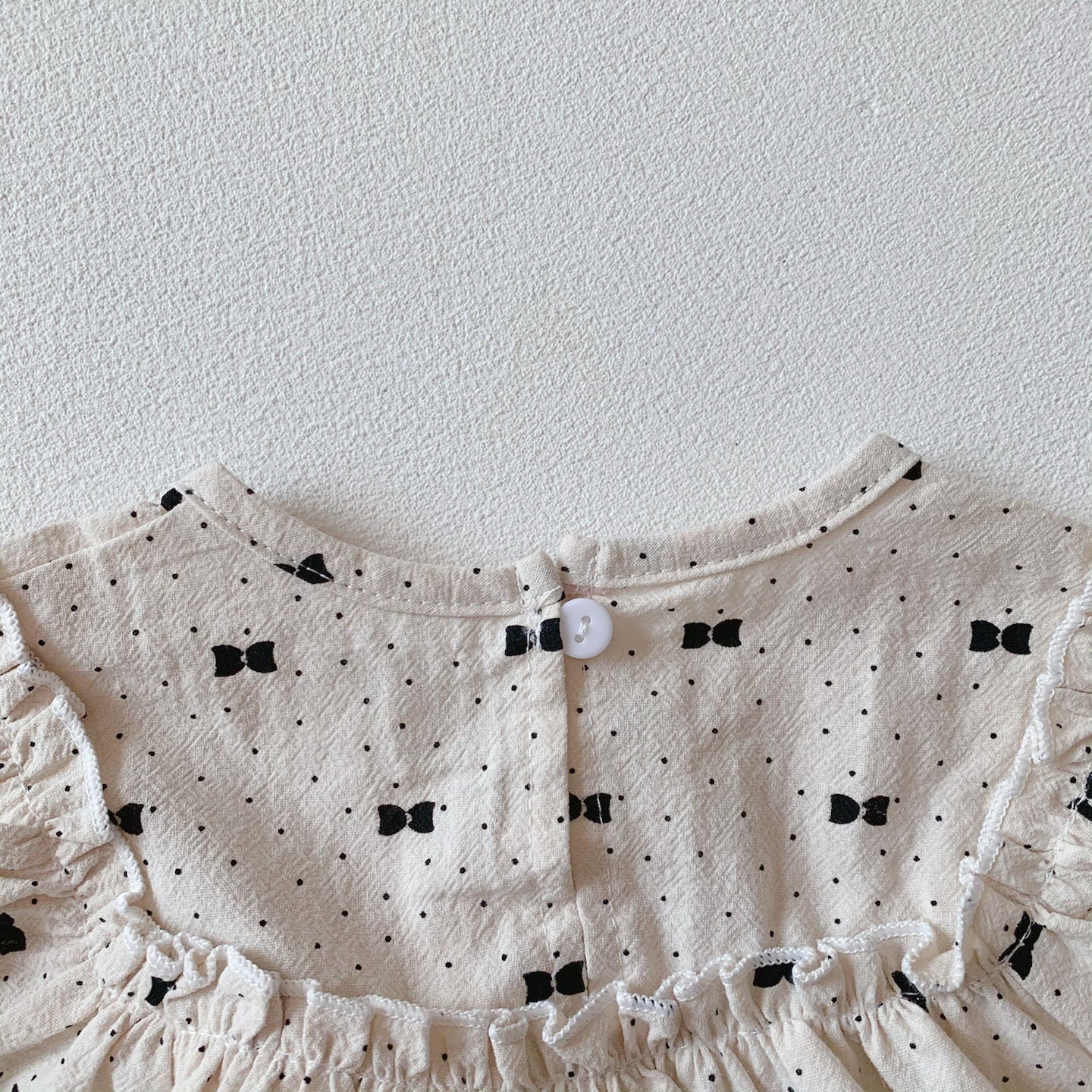 Baby girl wearing a stylish bow and polka dot A-line long sleeves shirt combo in apricot color.