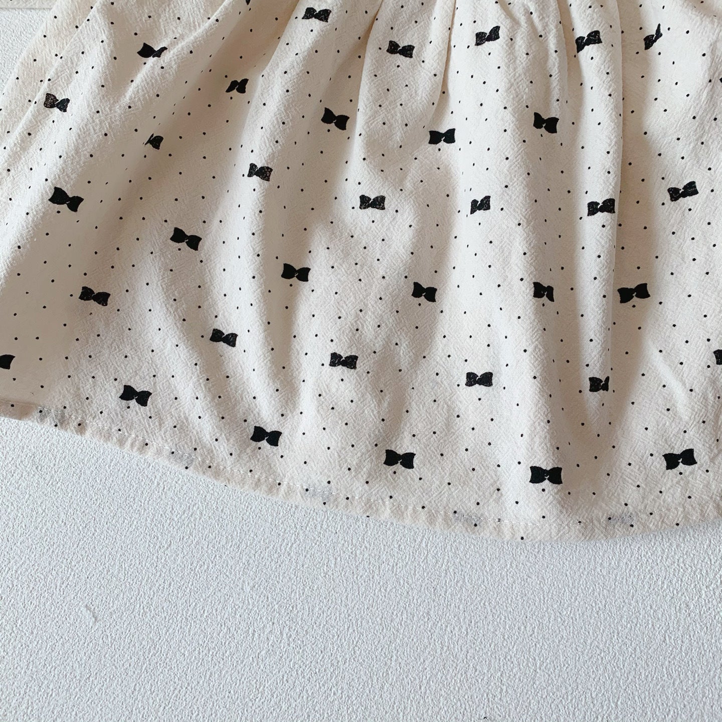 Baby girl wearing a stylish bow and polka dot A-line long sleeves shirt combo in apricot color.