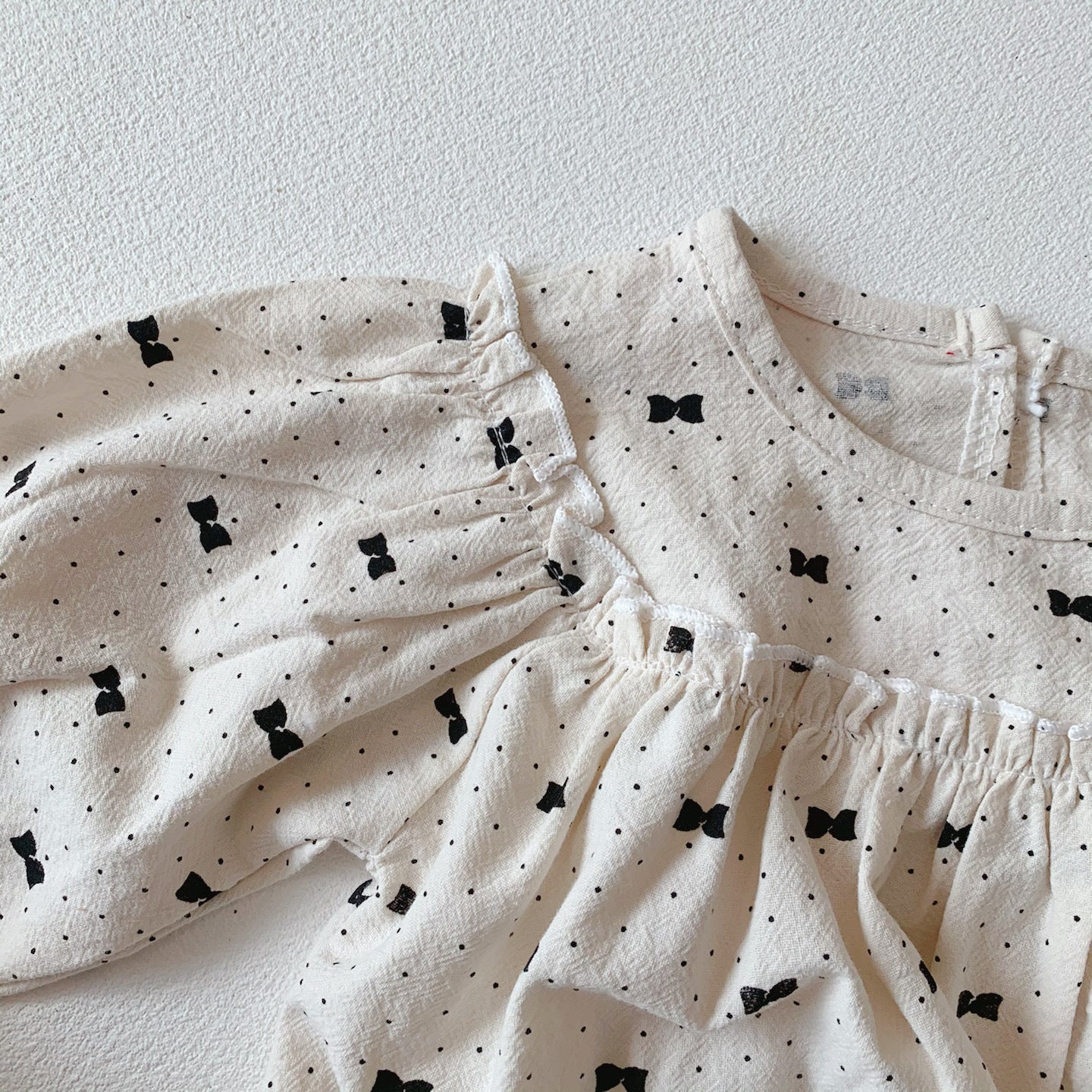 Baby girl wearing a stylish bow and polka dot A-line long sleeves shirt combo in apricot color.