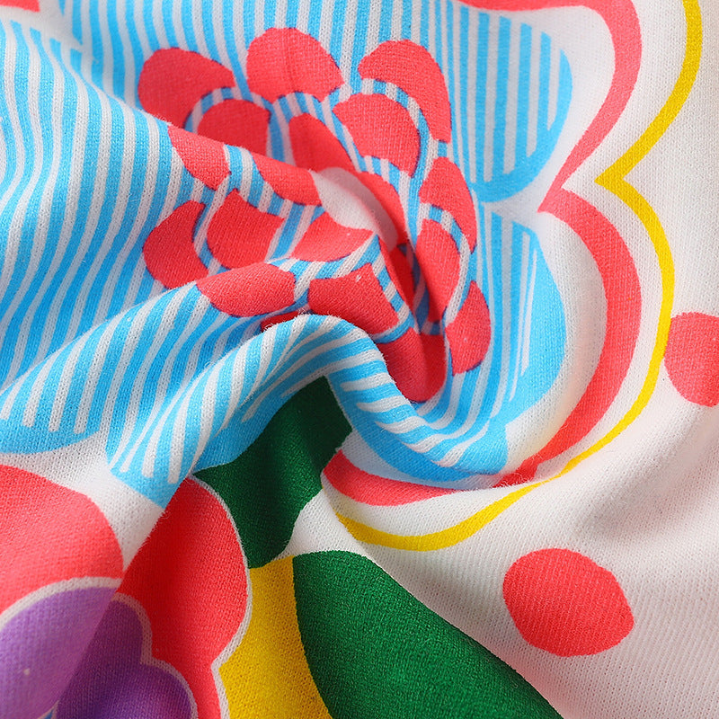 A cute baby girl wearing a sleeveless cartoon print summer dress in white, featuring colorful floral and rainbow patterns.