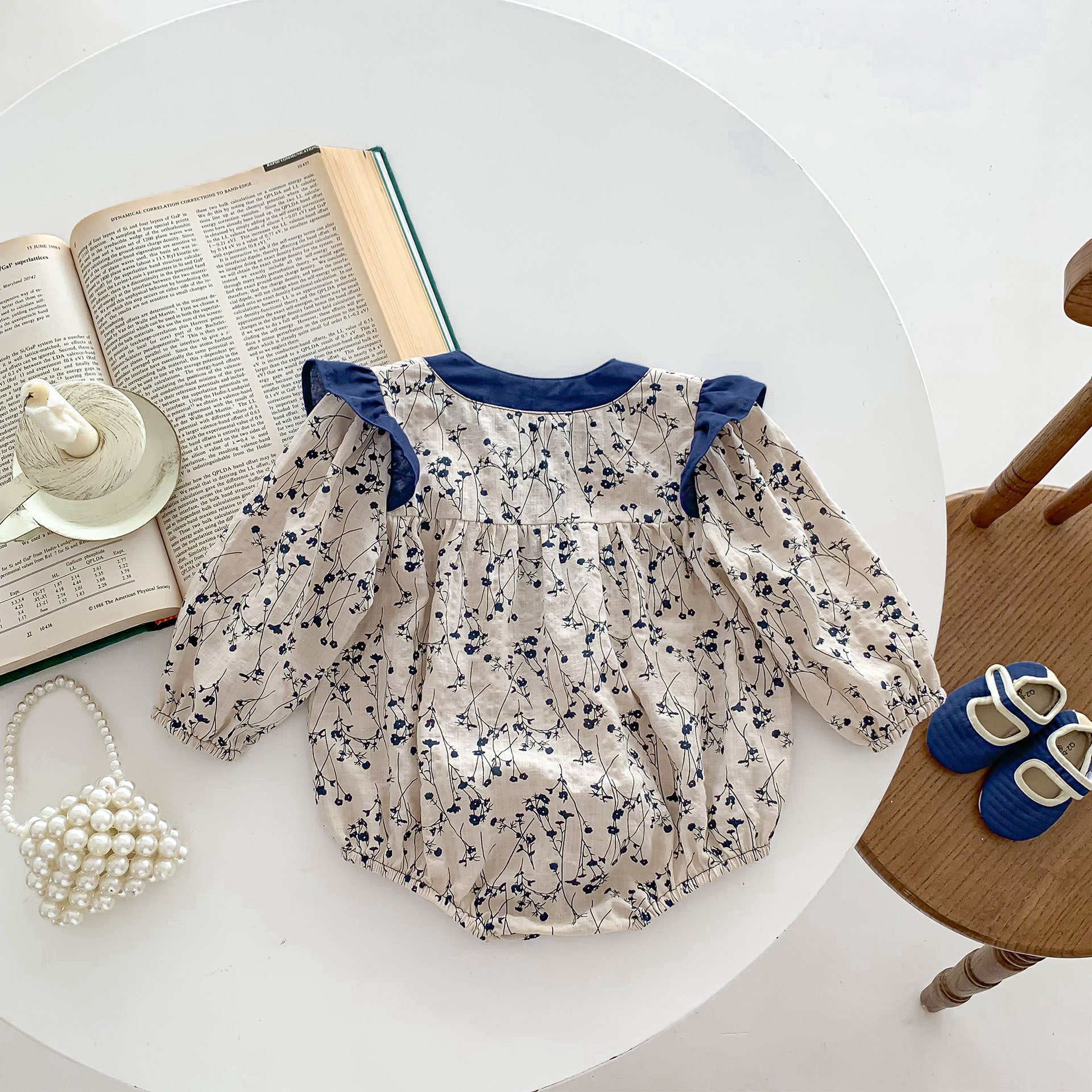 Baby girl onesie in vibrant blue with floral graphic design, made from soft cotton material.