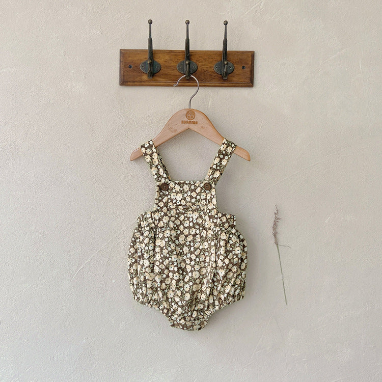 Baby girl wearing a cute floral print overall triangle onesie with straps in yellow color.