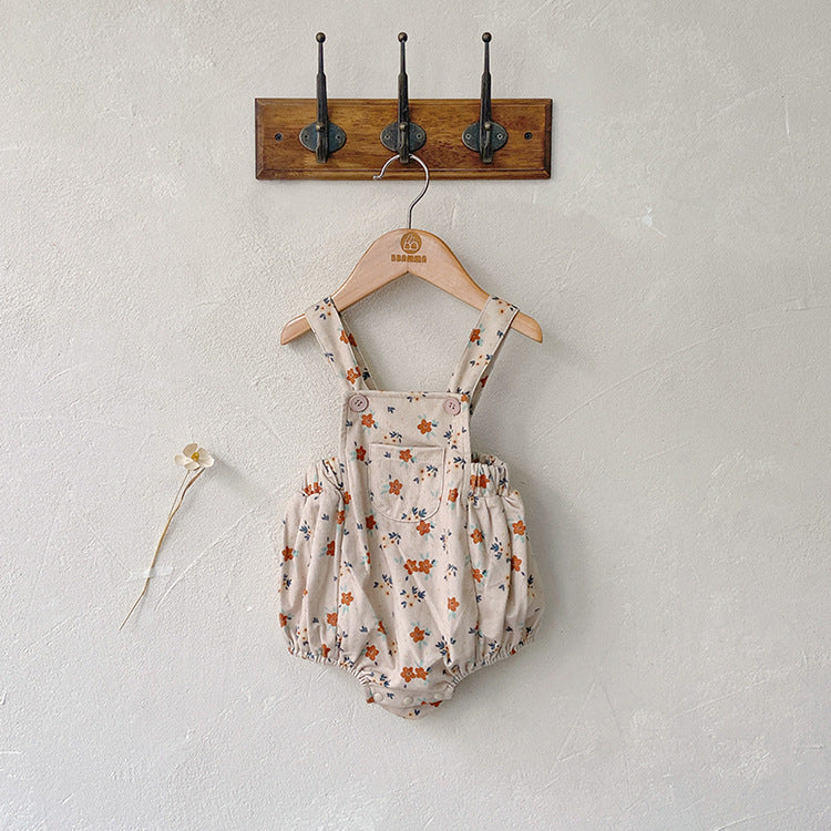 Baby girl wearing a cute floral print overall triangle onesie with straps in yellow color.