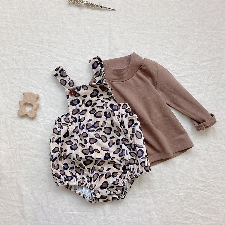 Baby girl wearing a cute floral print overall triangle onesie with straps in yellow color.