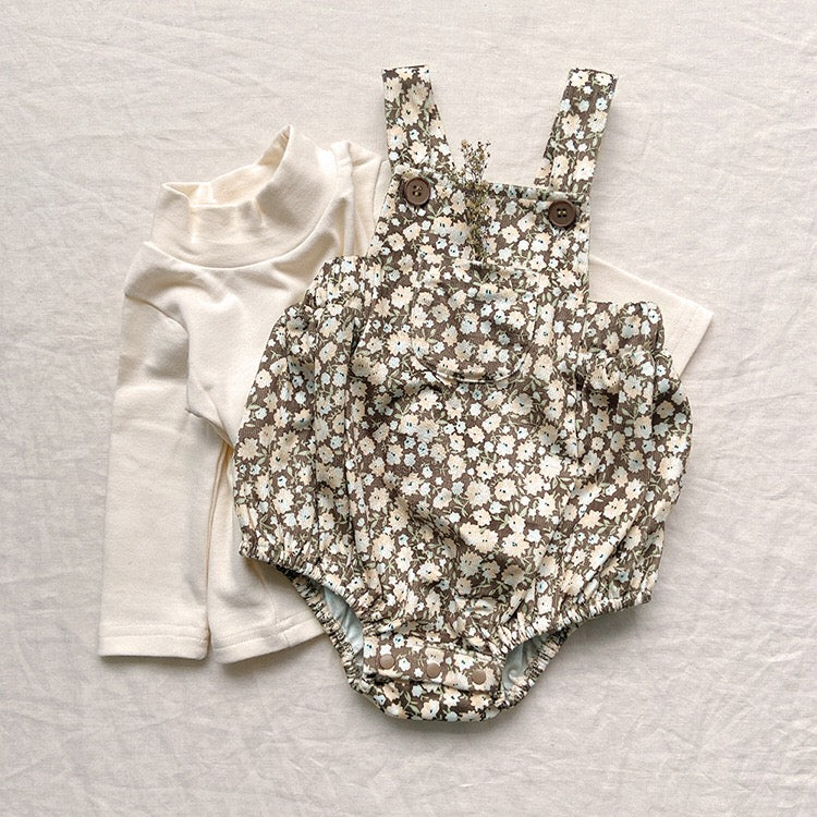 Baby girl wearing a cute floral print overall triangle onesie with straps in yellow color.