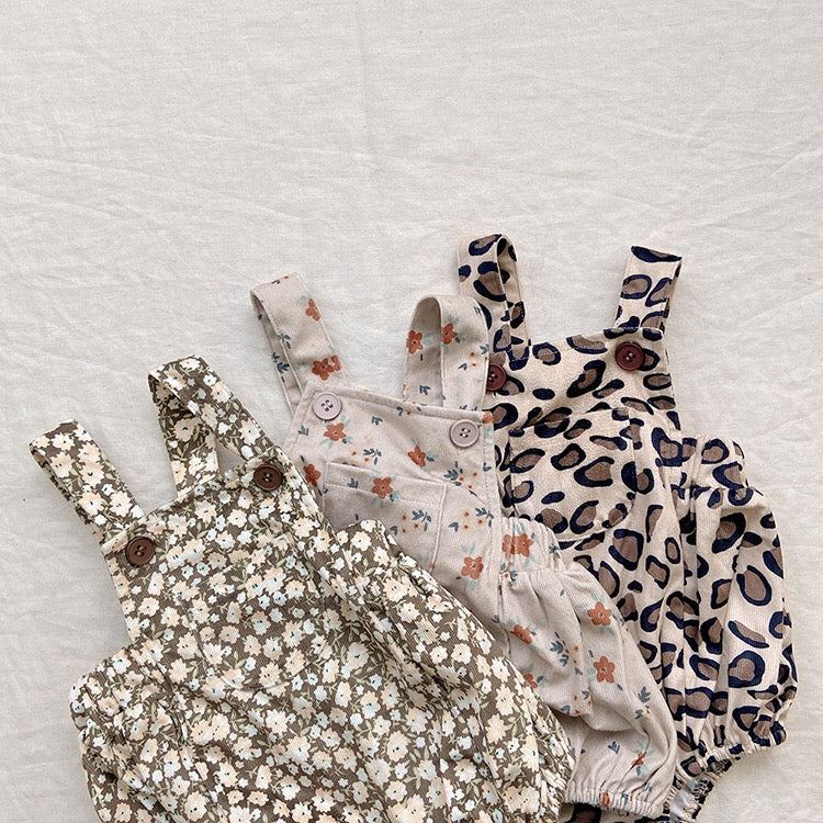 Baby girl wearing a cute floral print overall triangle onesie with straps in yellow color.