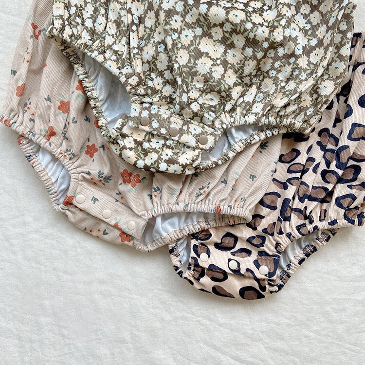 Baby girl wearing a cute floral print overall triangle onesie with straps in yellow color.