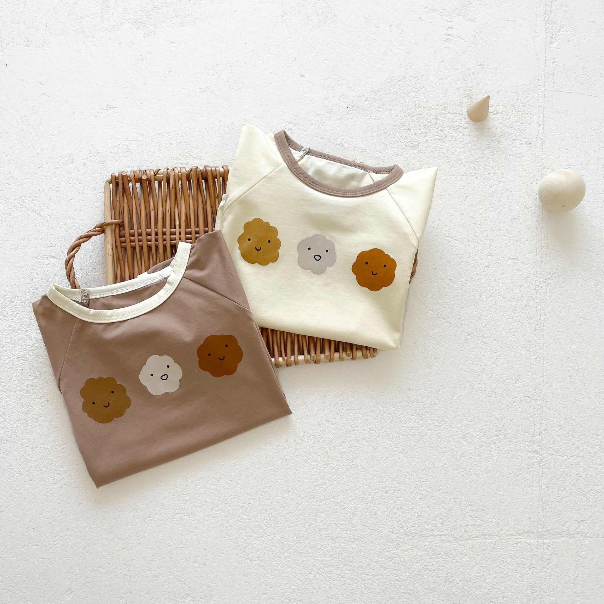 Baby girl wearing a cute smile face print onesie, showcasing a soft cotton blend fabric and short sleeves.