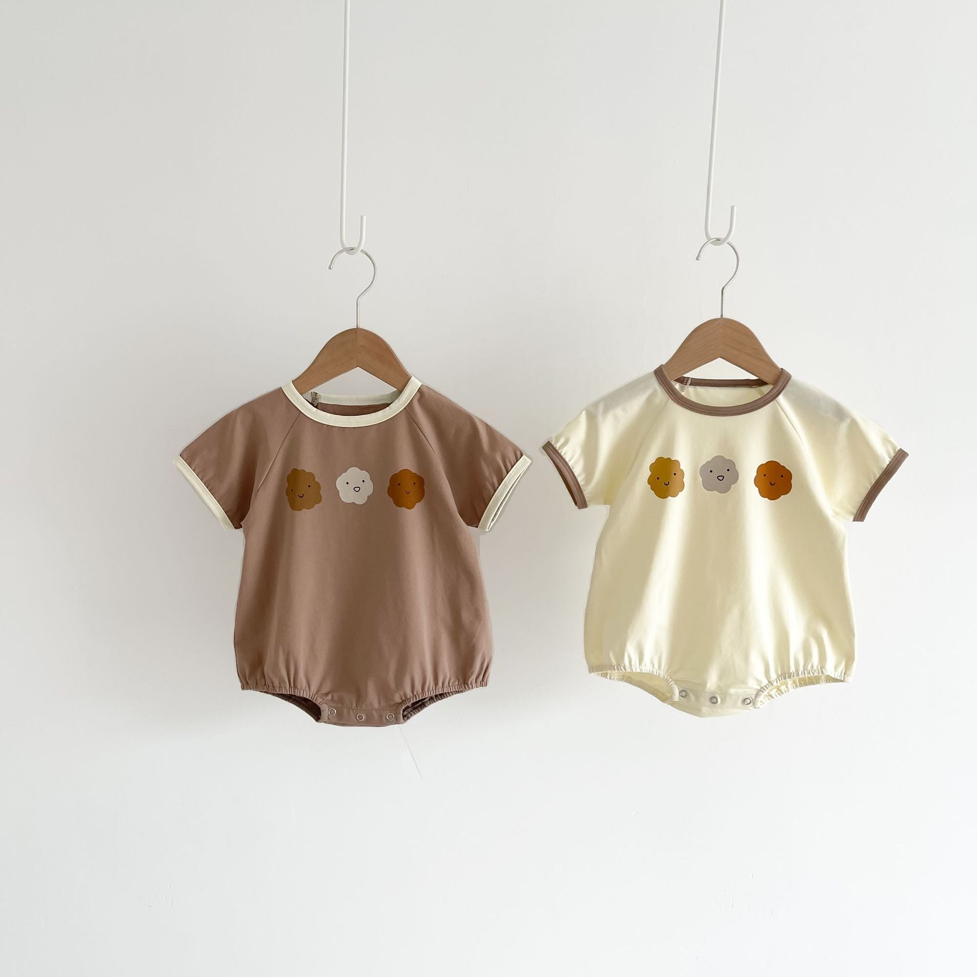 Baby girl wearing a cute smile face print onesie, showcasing a soft cotton blend fabric and short sleeves.