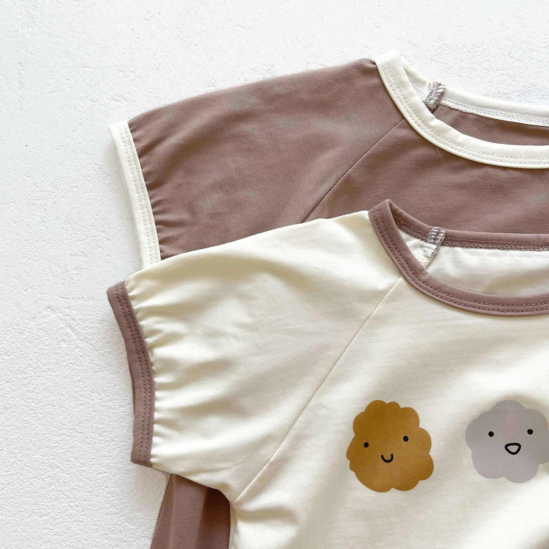 Baby girl wearing a cute smile face print onesie, showcasing a soft cotton blend fabric and short sleeves.