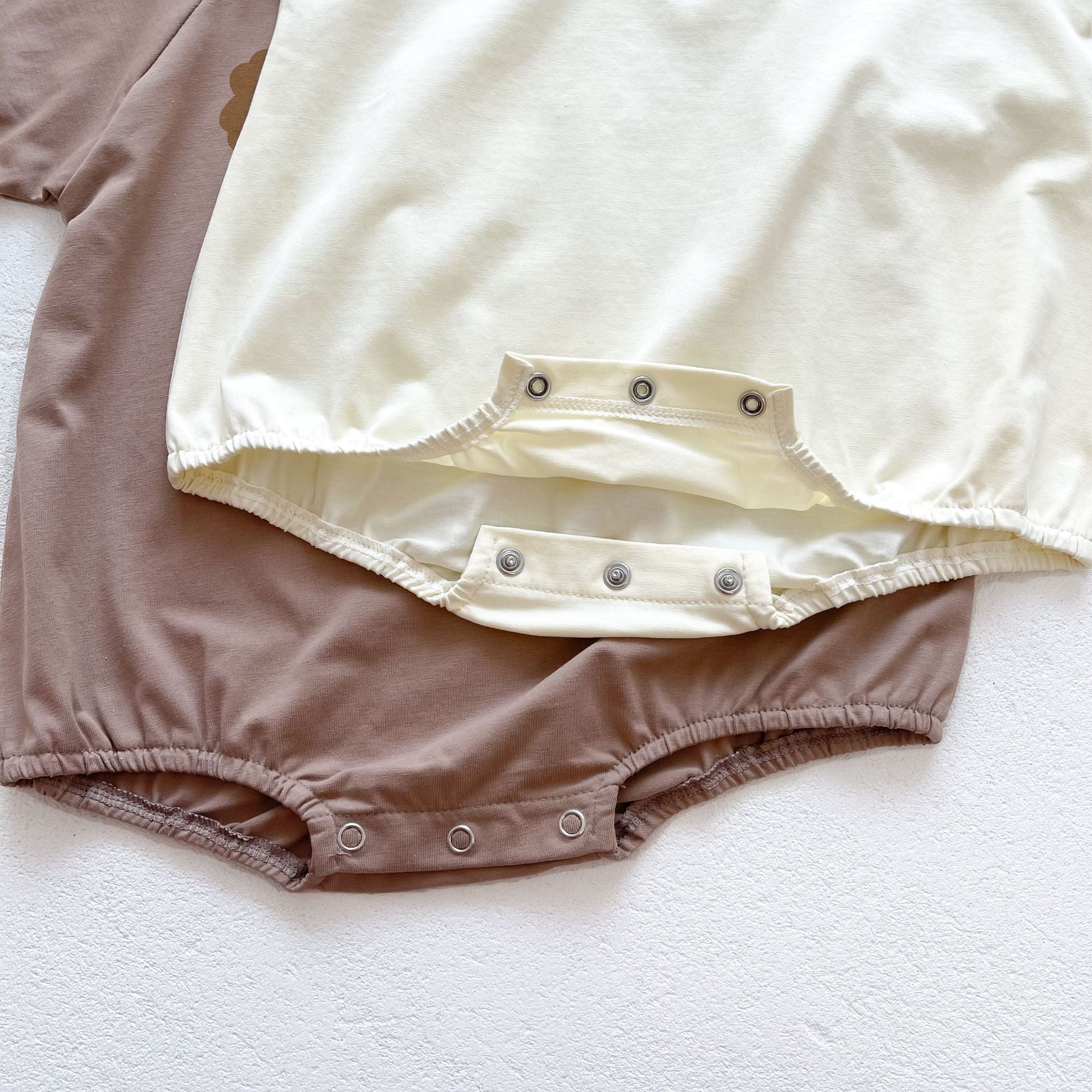 Baby girl wearing a cute smile face print onesie, showcasing a soft cotton blend fabric and short sleeves.