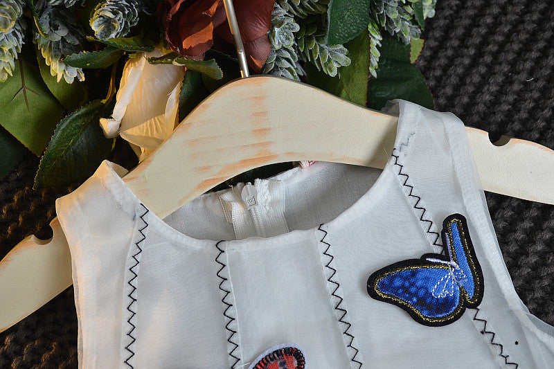 A charming white sleeveless dress for baby girls featuring dimensional butterfly embroidery and lace patchwork, perfect for summer occasions.