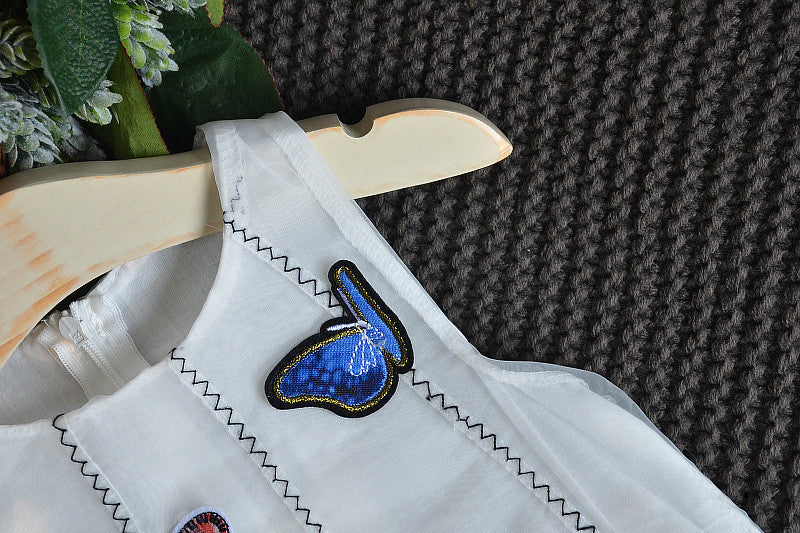 A charming white sleeveless dress for baby girls featuring dimensional butterfly embroidery and lace patchwork, perfect for summer occasions.