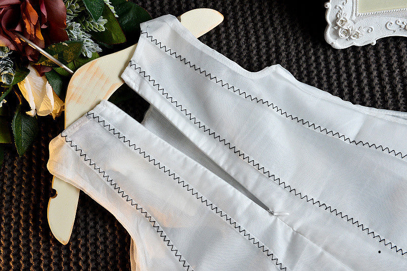 A charming white sleeveless dress for baby girls featuring dimensional butterfly embroidery and lace patchwork, perfect for summer occasions.