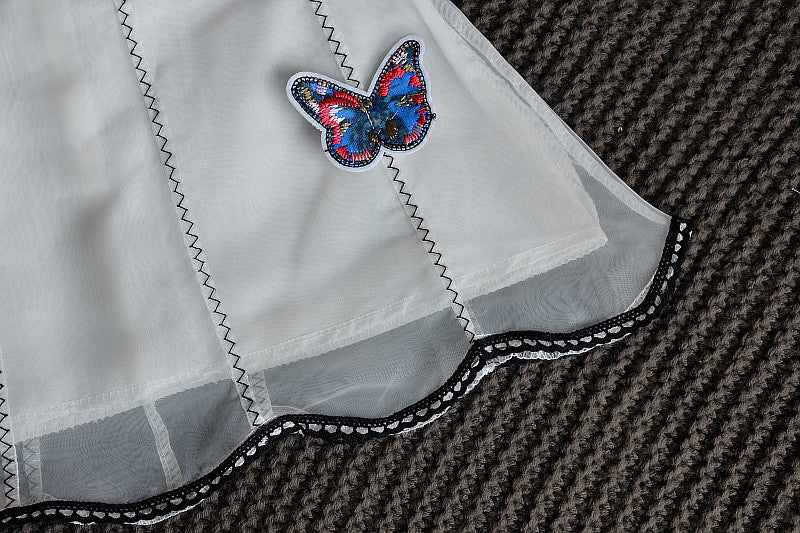 A charming white sleeveless dress for baby girls featuring dimensional butterfly embroidery and lace patchwork, perfect for summer occasions.