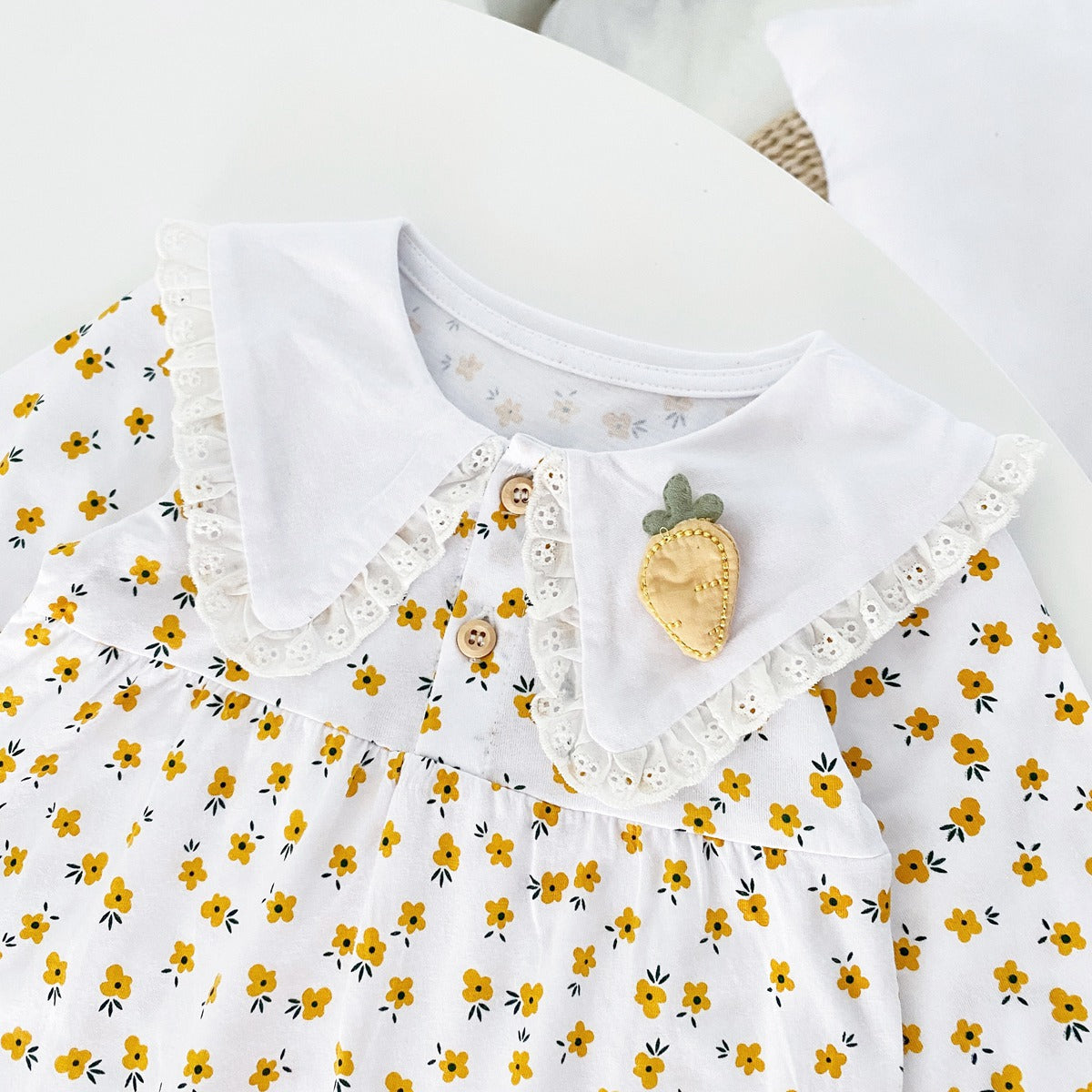 Baby girl romper featuring a ditsy floral print and embroidered carrot pattern, available in pink and yellow colors.