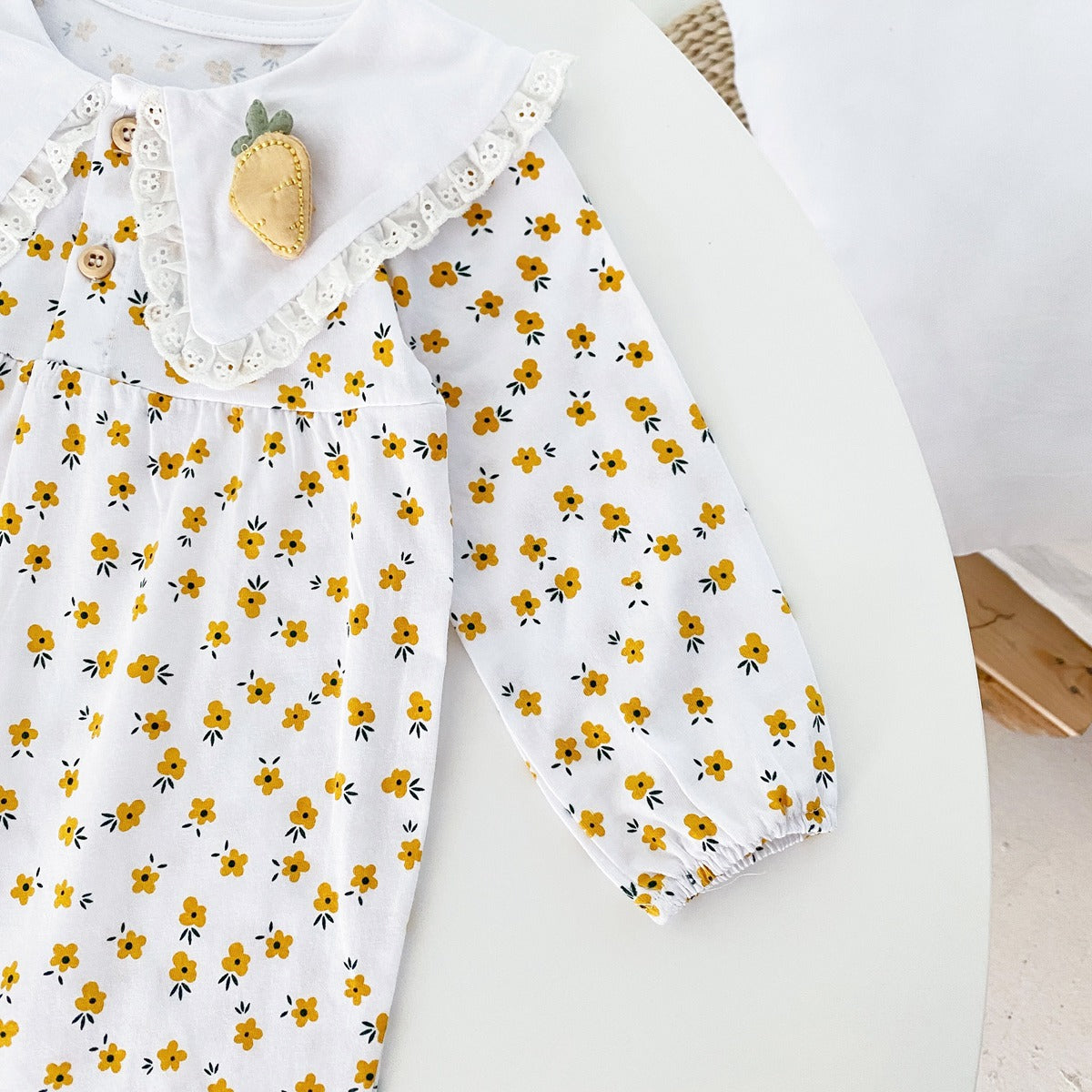 Baby girl romper featuring a ditsy floral print and embroidered carrot pattern, available in pink and yellow colors.