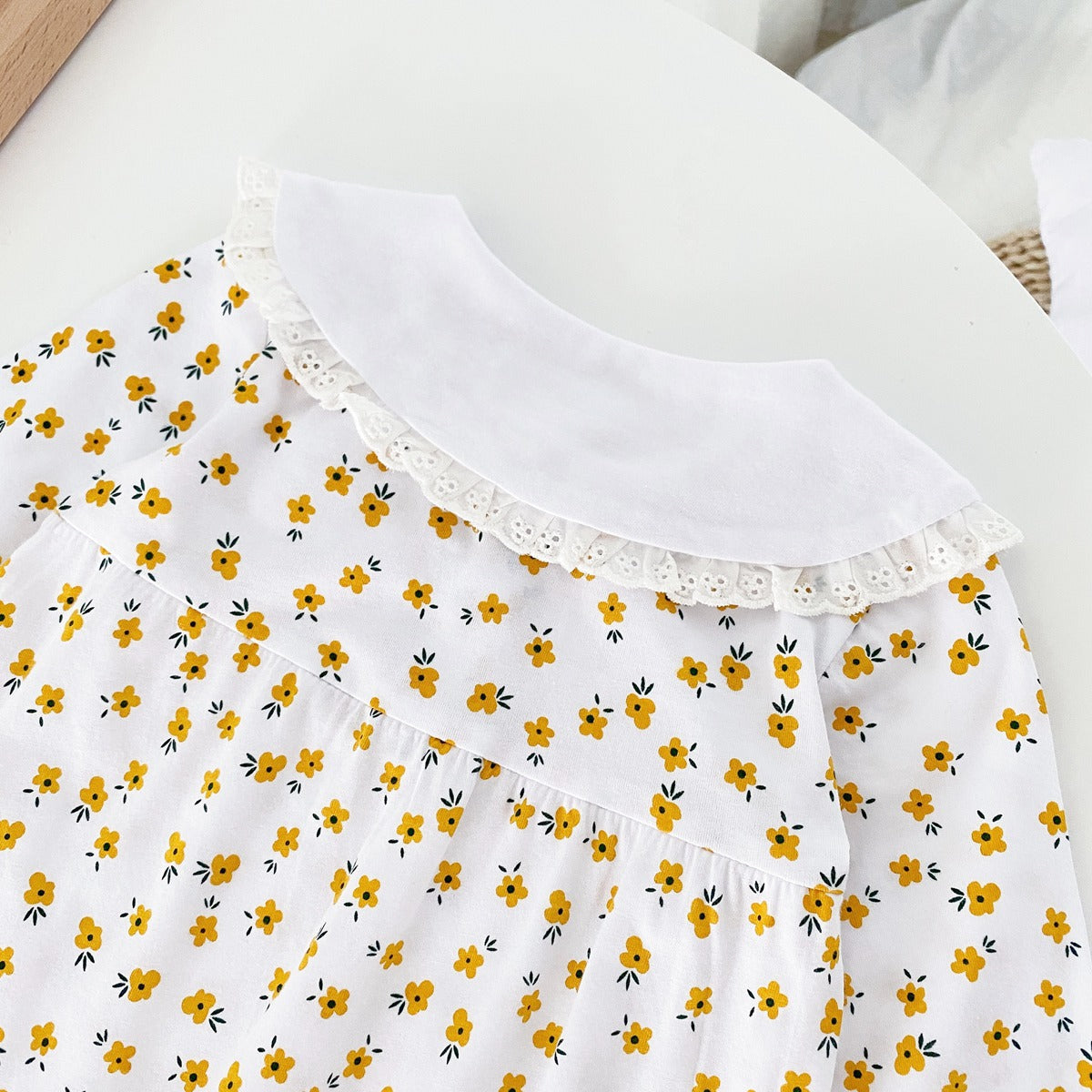 Baby girl romper featuring a ditsy floral print and embroidered carrot pattern, available in pink and yellow colors.