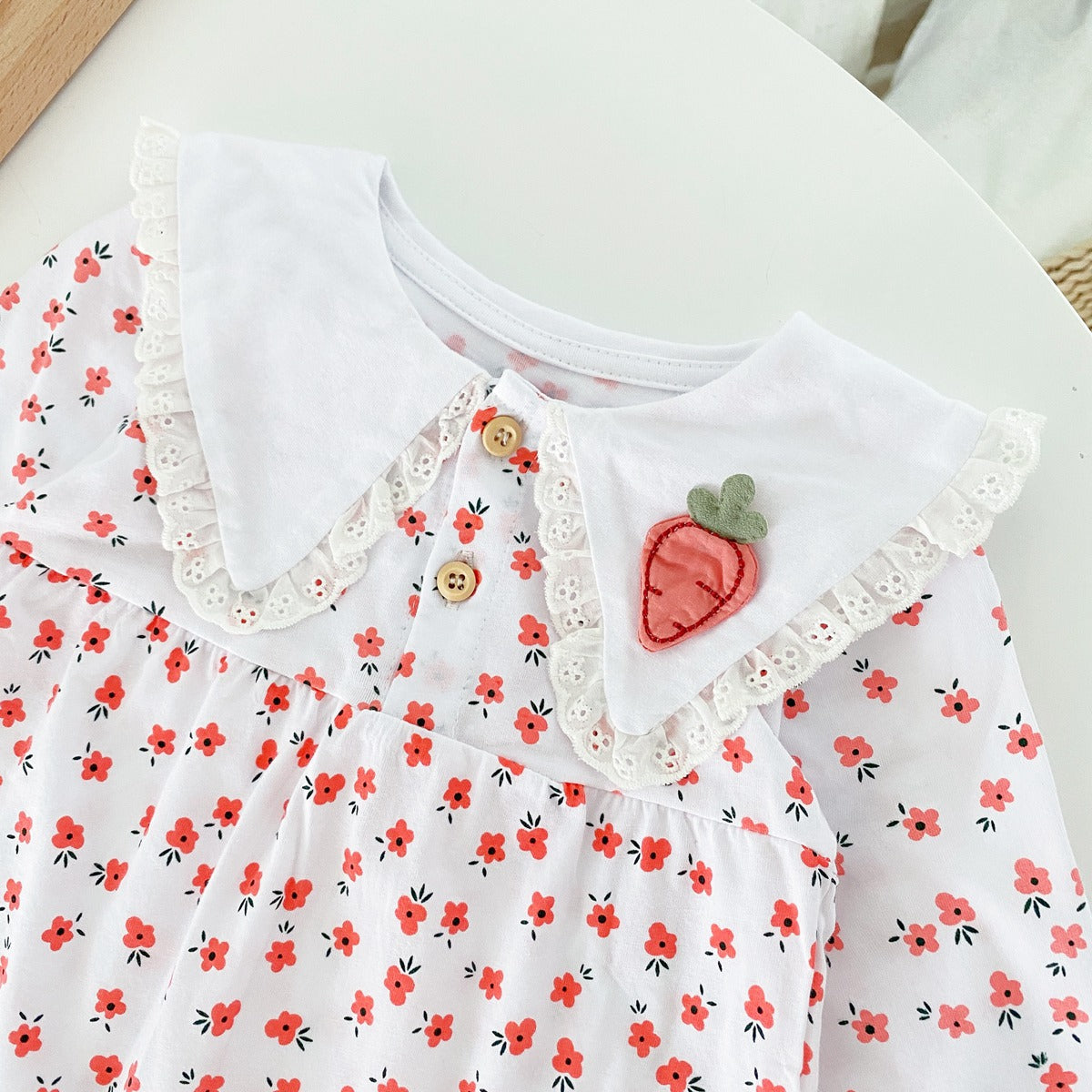 Baby girl romper featuring a ditsy floral print and embroidered carrot pattern, available in pink and yellow colors.