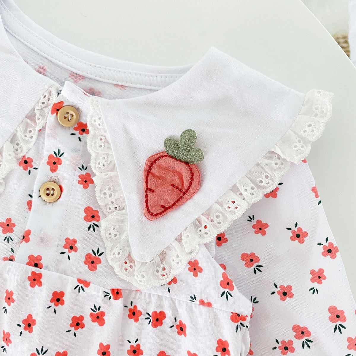 Baby girl romper featuring a ditsy floral print and embroidered carrot pattern, available in pink and yellow colors.