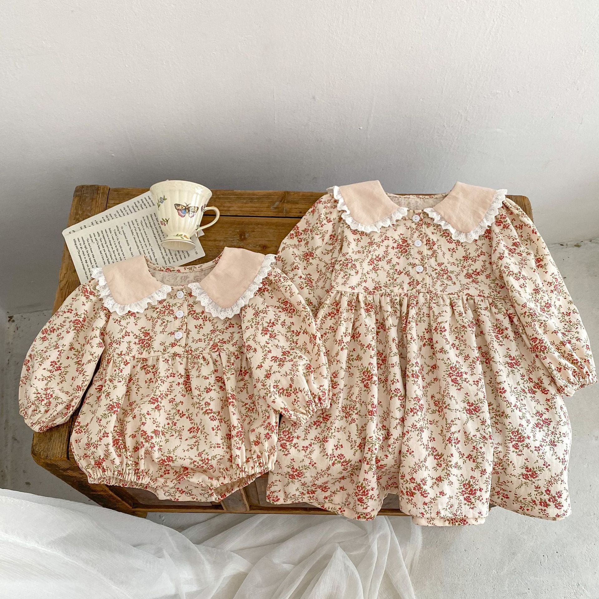 Adorable baby girl wearing a long sleeve onesie dress with ditsy flower graphic and mesh patched design in pink.