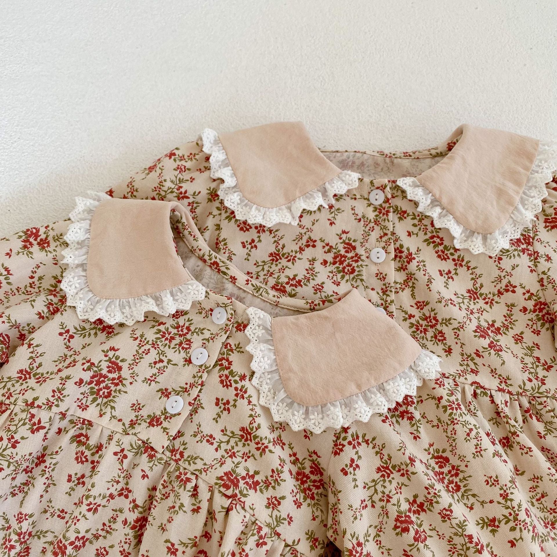 Adorable baby girl wearing a long sleeve onesie dress with ditsy flower graphic and mesh patched design in pink.