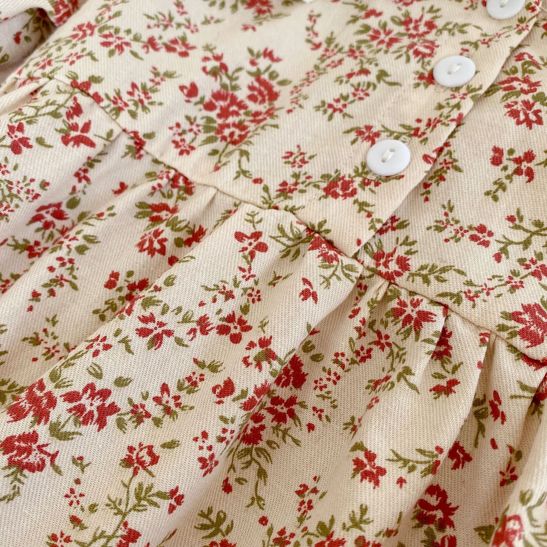 Adorable baby girl wearing a long sleeve onesie dress with ditsy flower graphic and mesh patched design in pink.